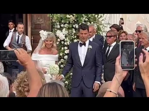 Il bacio degli sposi fuori dalla chiesa, l’applauso di fan, amici e parenti