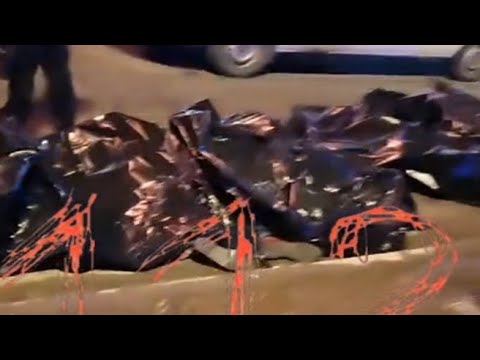 Cadaveri nei sacchi allineati sul marciapiede davanti al teatro